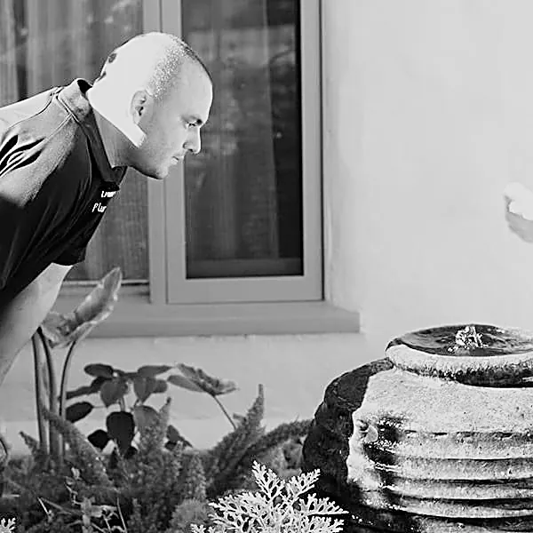 Danny working on a tiered garden fountain outside a Spanish-style house.