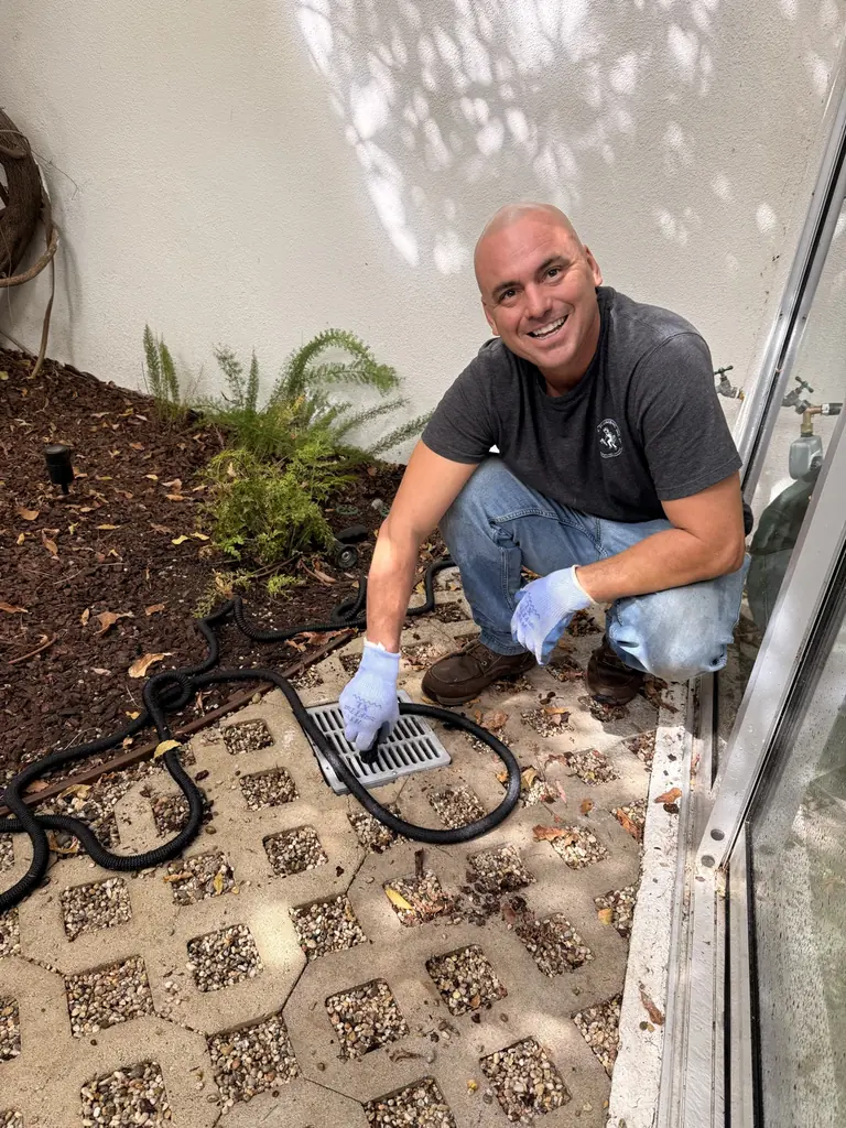 Dan’s Plumbing team member working at an outdoor area drain