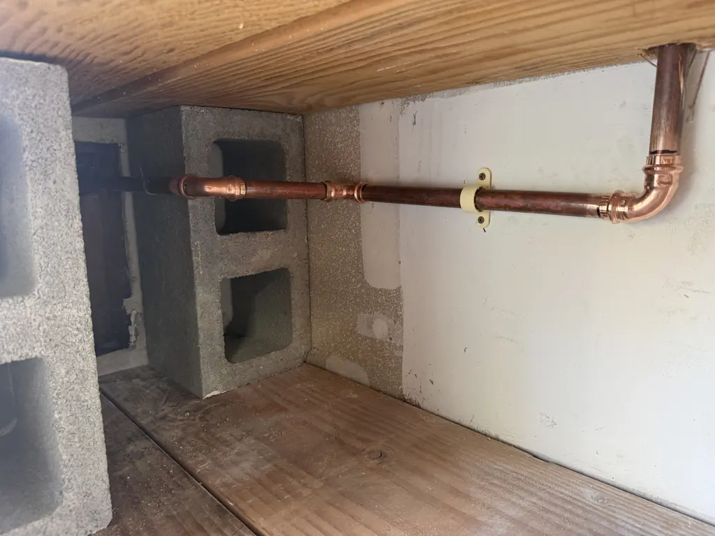 The new copper line strapped along the wall, past the slab leak