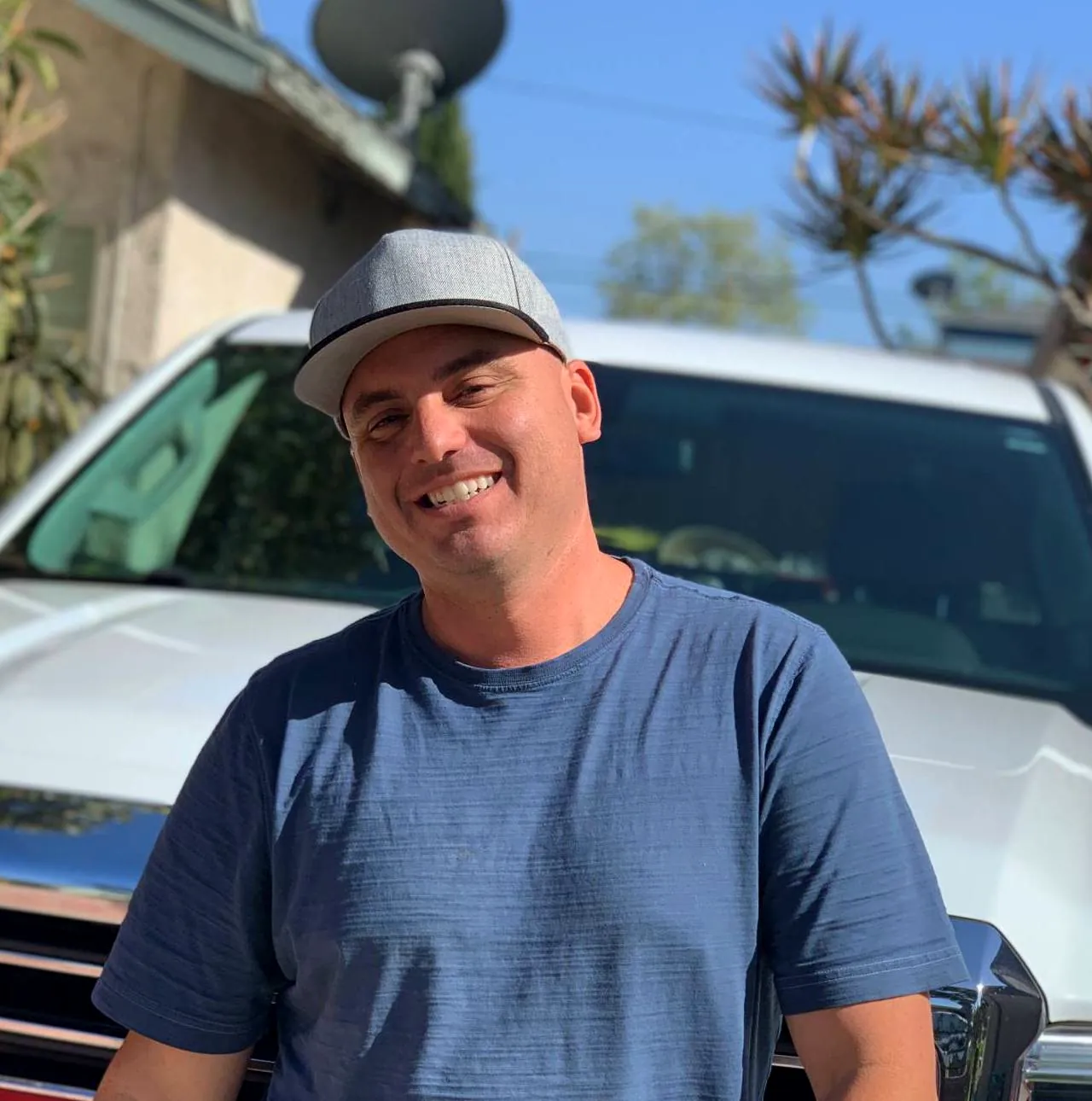 Dan standing in front of his white work truck, smiling.