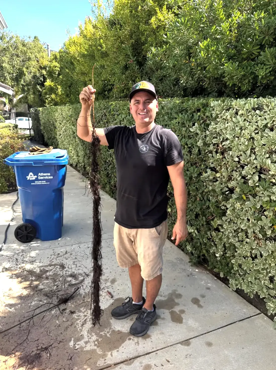 Dan holding up a long rope of tree roots he pulled out of a drain line.