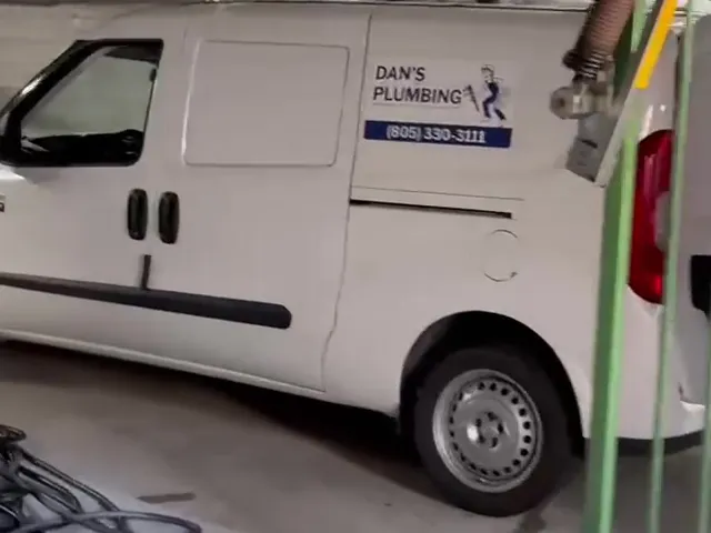 The Dan's Plumbing van, white with the logo and phone number on the side, parked at a job.